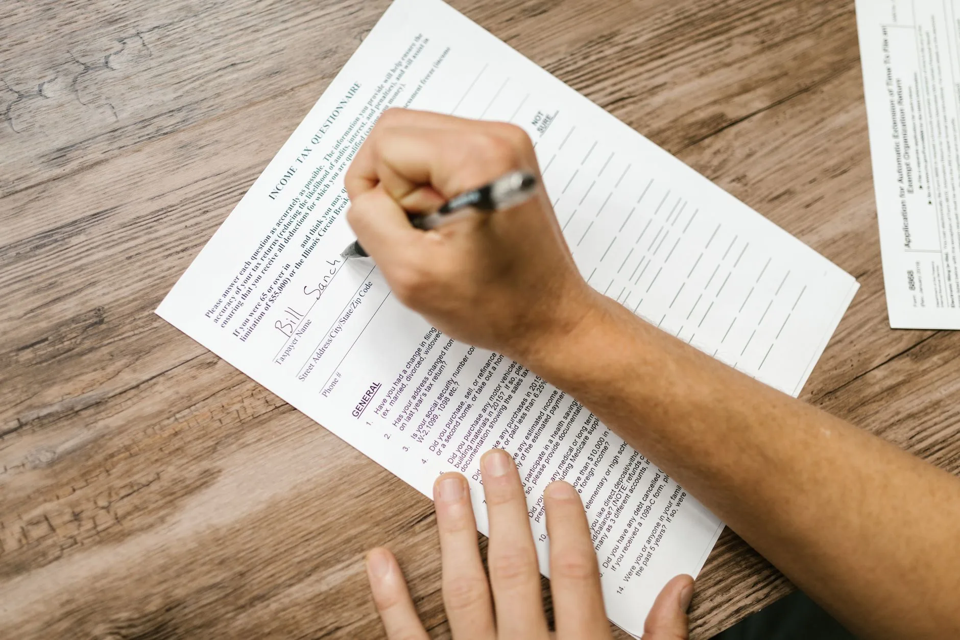 Una persona llenando un formulario de impuestos en un escritorio con una calculadora y documentos