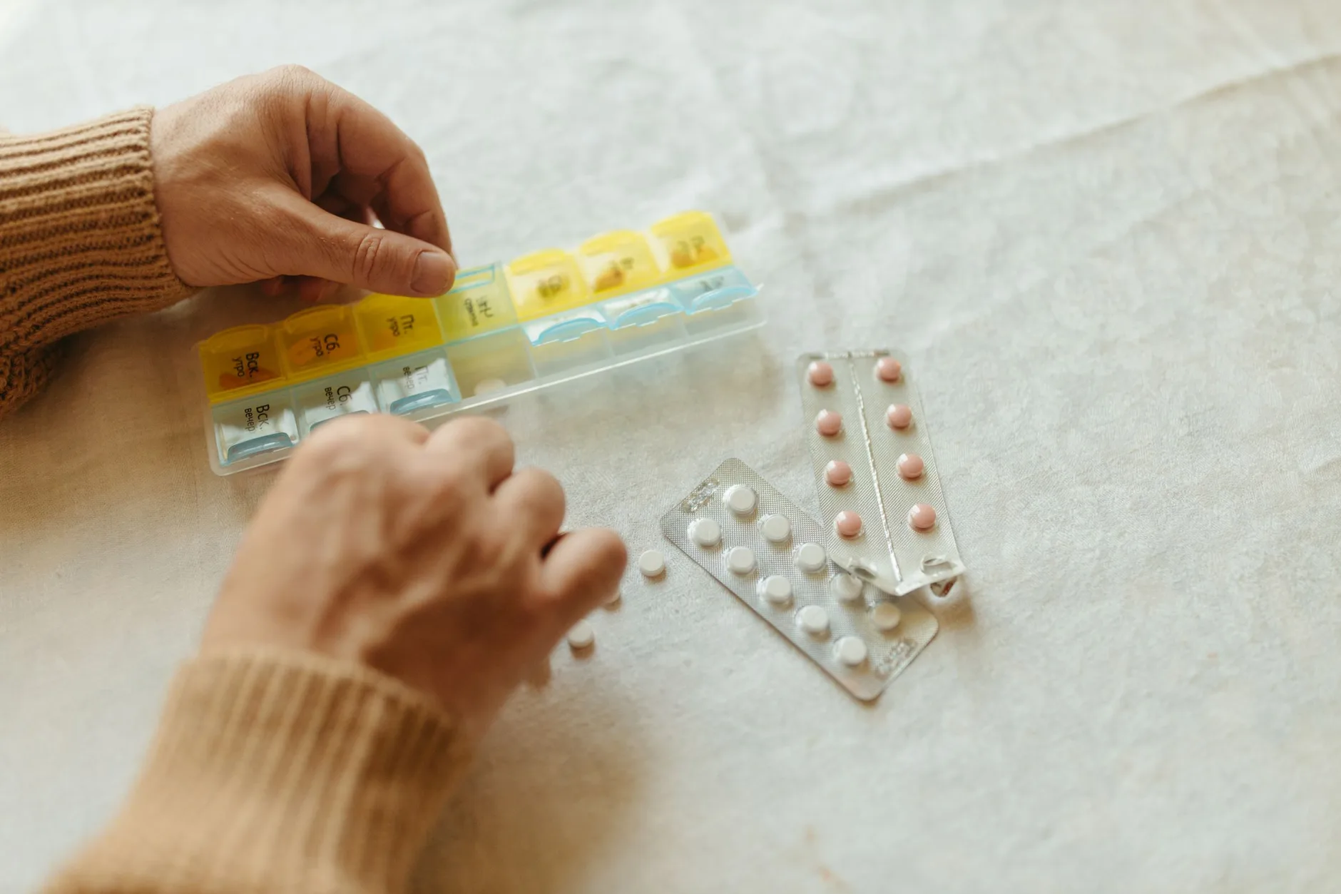 A Medicare member sorting their prescriptions into a weekly pill organizer at home
