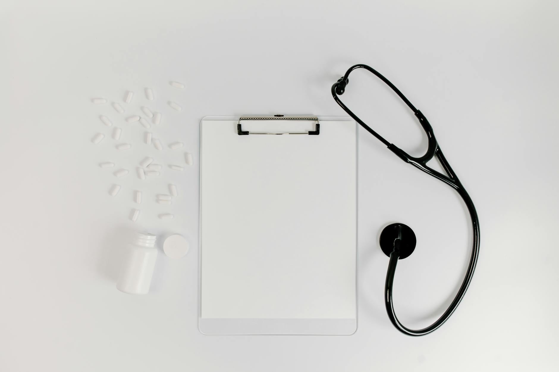 Pill bottles arranged with a stethoscope on a desk, representing prescription drug coverage