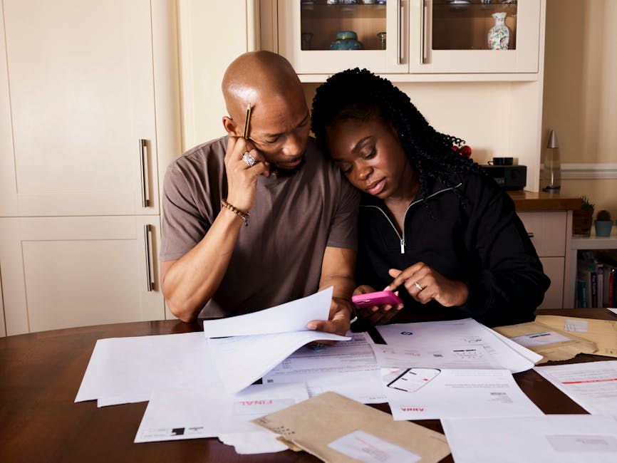 A couple at a kitchen table organizing household financial documents and policies