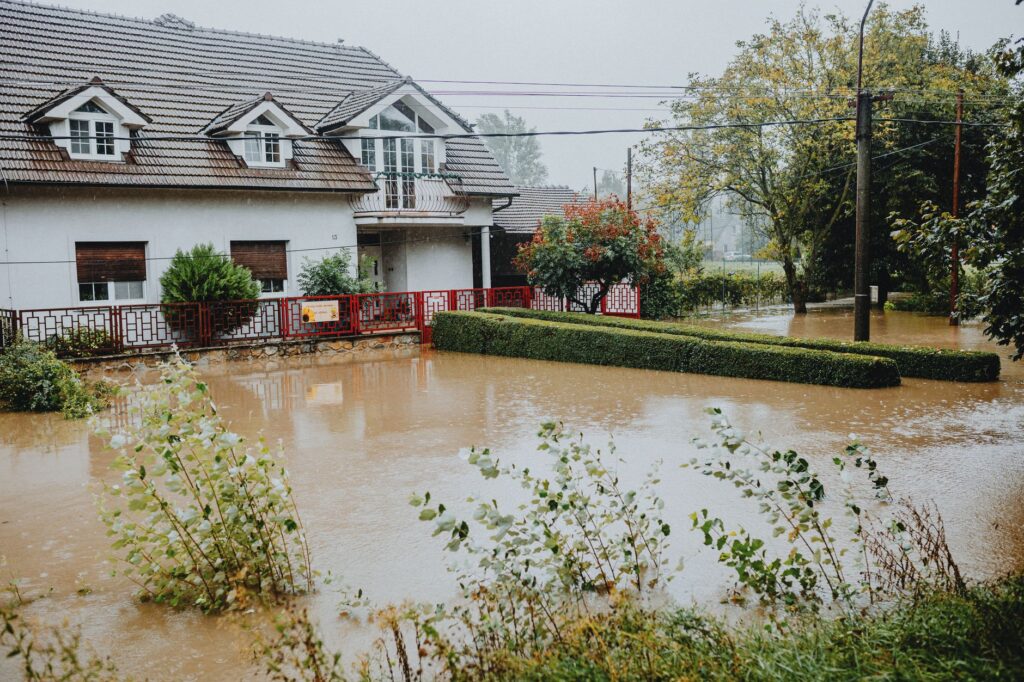 A flooded residential street with water surrounding homes after a storm