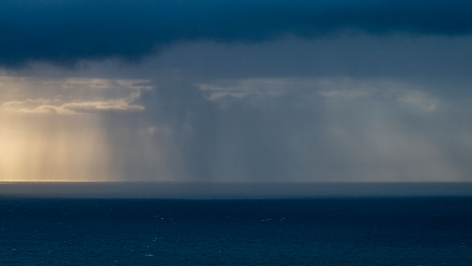 Dark storm clouds and heavy rain moving over a coastal neighborhood