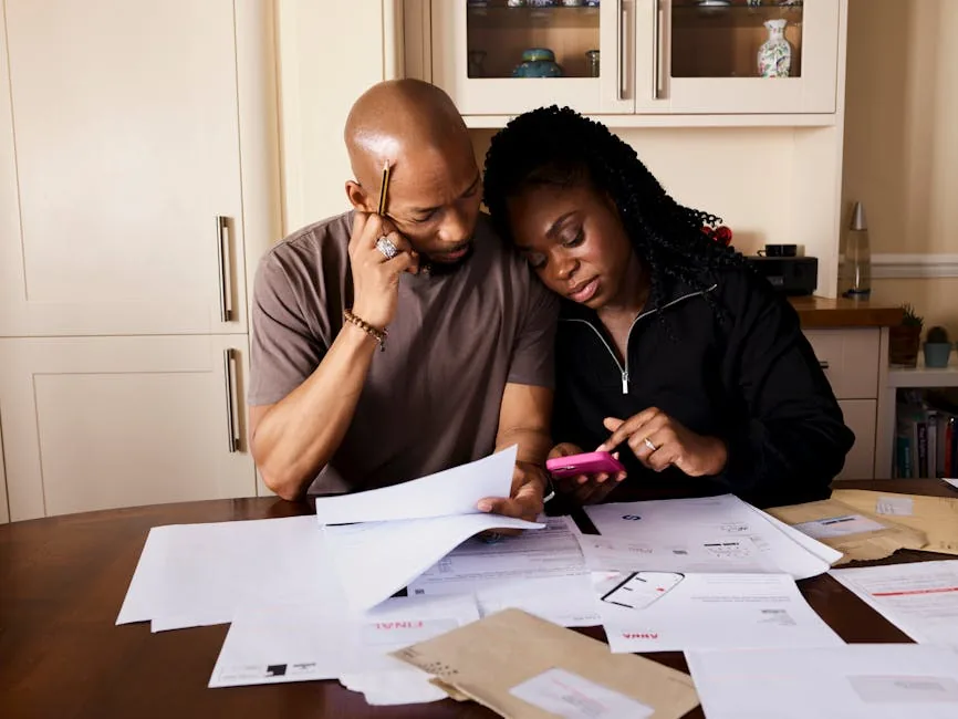 Una pareja en la mesa de la cocina organizando documentos y pólizas financieras del hogar
